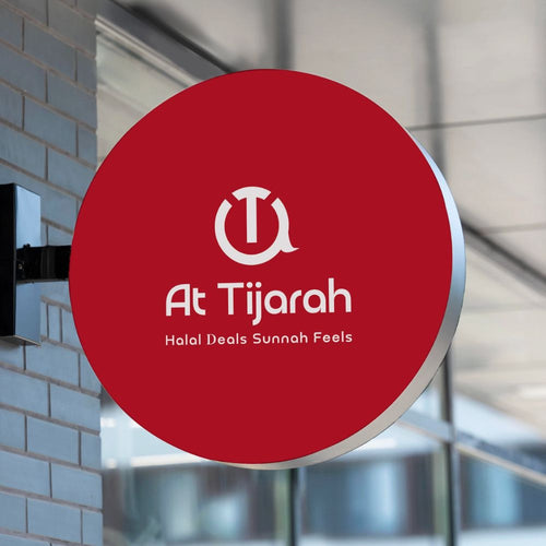 Red circular sign with 'At Tijarah' logo and text on a building exterior.