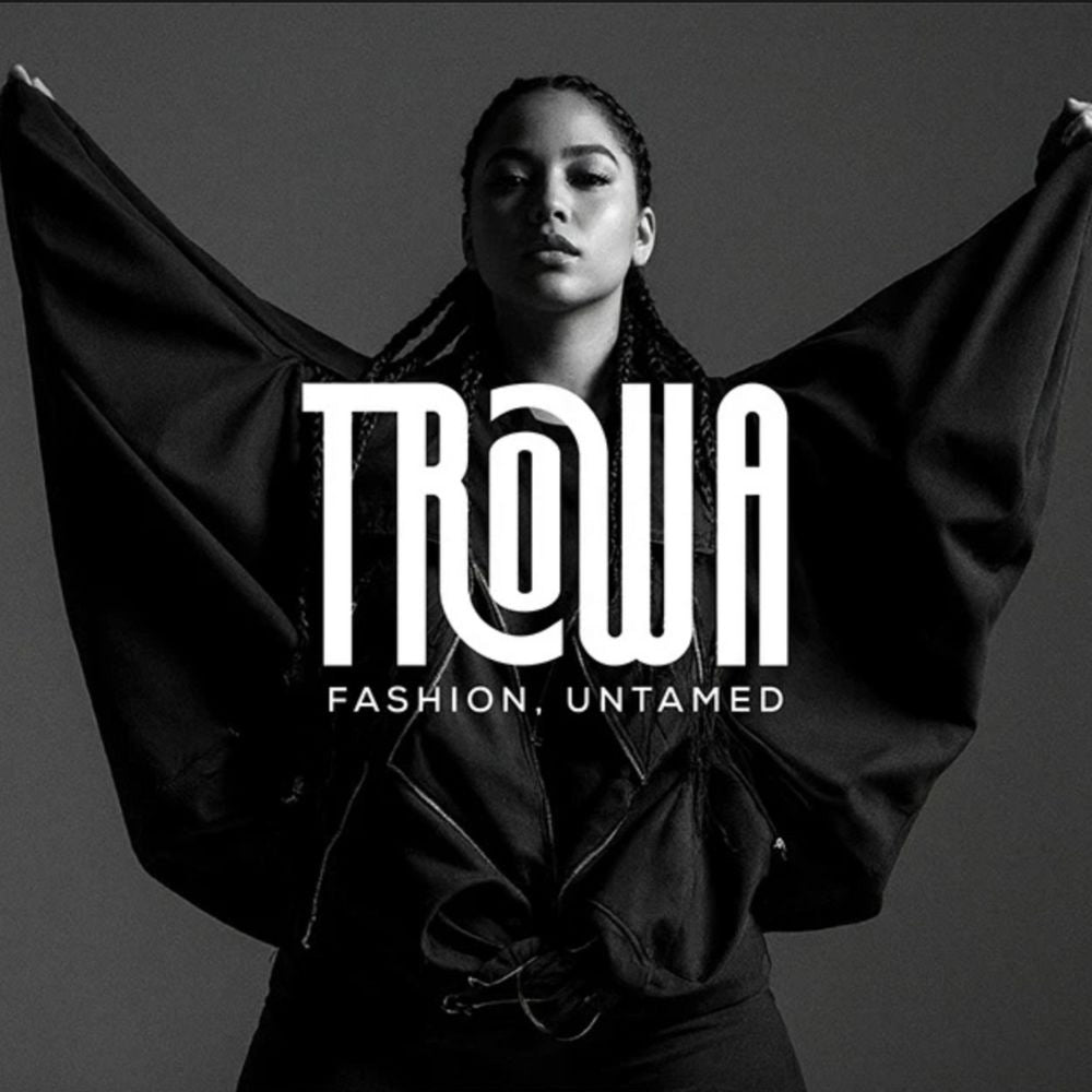 Person holding a black garment with 'Trowa' brand logo and text on a gray background