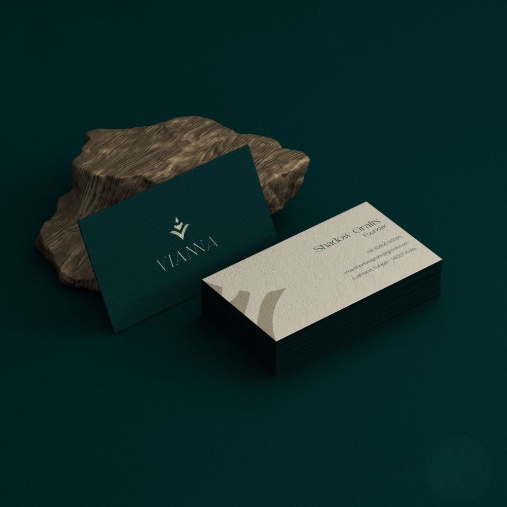 Two business cards on a dark surface with a brand logo.